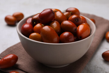 Fresh Ziziphus jujuba fruits with bowl and napkin on table, closeup