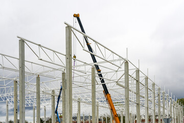 crane with telescopic boom in the assembly of metal structures of an industrial building © Zigmunds