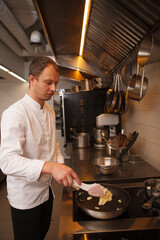 Vertical shot of a professional cheffrying mashed potatoes on the frying pan at the restaurant