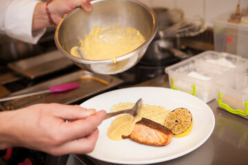 Chef coating fried salmon with delicious sauce