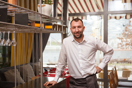 Cheerful friendly mle waiter welcoming you at the restaurant