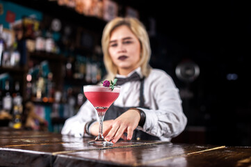 Expert woman mixologist demonstrates the process of making a cocktail behind bar