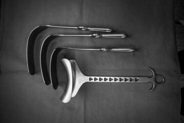 some various surgical abdominal retractors lie side by side on a green base
