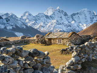 view through stone fence to old farm house on pasture in highland in Nepal