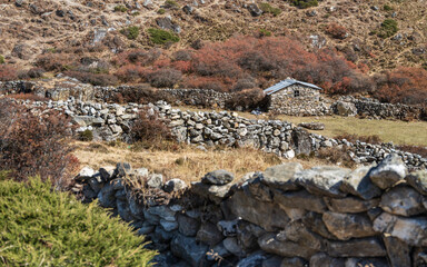 Fototapeta na wymiar view to old stone fence and farm house on yaks pasture in Nepal