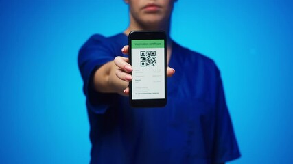 Woman surgeon in medical uniform showing vaccination passport with qr code on phone, international coronavirus vaccine certificate on mobile device, digital covid 19 passport, green zone.