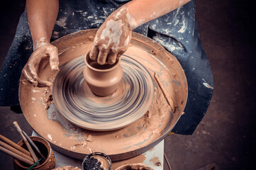 Potter female student creates a new pottery from clay on a potter's wheel. Handmade. Close-up.