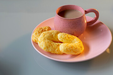 Rustic porcelain cup with cappuccino, cheese bread with parmesan, known as chipa