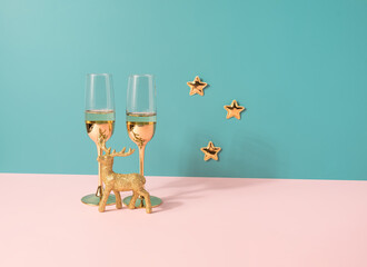 Champagne glasses with golden ornaments on a two tone pastel background. New Year celebration background