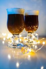 Cups of irish coffee with irish whiskey caramelized cane sugar and cream on top with small shining lights around