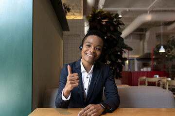 view from the camera, african american business woman looks at the camera and smiles talks, and rejoices shows thumbs up approvingly, video call laptop