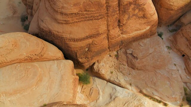 Aerial Circling Over A Large Desert Rock Formation And Ancient Tombs On A Bright Sunny Day - Hegra, Saudi Arabia