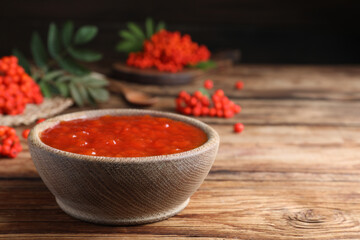 Delicious rowan jam in bowl on wooden table. Space for text