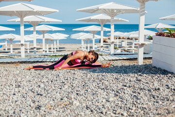beautiful woman engaged in fitness gymnastics yoga asana on the beach by the sea
