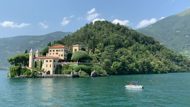Landscape of Como Lake shore and Villa del Balbianello mansion house.  Moving boat in Como lake. Tremezzina, Como Lake, Lombardy, Italy.