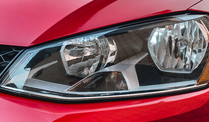 Close-up of halogen car headlights on a red car. Car details