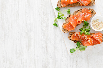 Whole grain rye bread open sandwiches with salted salmon on a white rustic wooden table. Healthy food. Top view