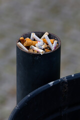 Lots of cigarette stubs crammed into the trash can post. The main subject stands out against a blurred background