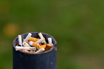 Lots of cigarette stubs crammed into the trash can post. The main subject stands out against a blurred background
