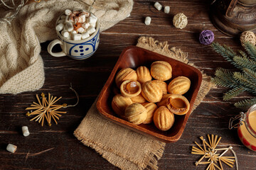 New Year's treat, homemade sponge cookies with condensed milk in a wooden bowl, on a table with fir branches, cups with cocoa, a blanket