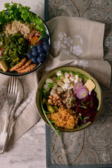 Bowl food. Vegetables, fruits, noodles, brown rice, lentils, cheese biscuits, feta cheese, Jerusalem artichoke in deep bowls. Linen napkin, forks.