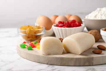 Marzipan and other ingredients for homemade Stollen on white marble table, closeup. Baking traditional German Christmas bread