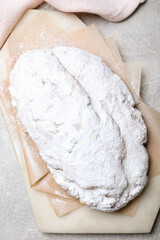Delicious Stollen sprinkled with powdered sugar on light table, top view