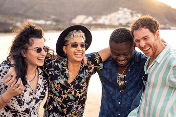 Group of happy multiracial friends having fun together on the beach, dancing and laughing. Mixed race people friendship concept. Multi ethnic students lifestyle