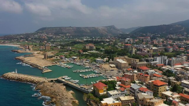 Aerial Forward Descending Beautiful Nautical Vessels At Harbor By City Against Cloudy Sky - Batroun, Lebanon