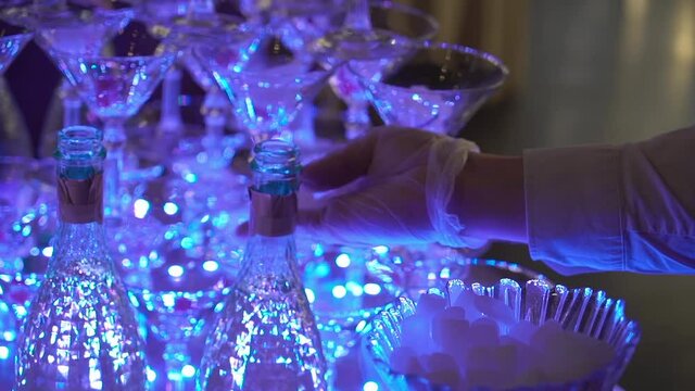 A pyramid of champagne glasses. Tower decorated with red cherry berries. Empty glasses for white sparkling wine at a restaurant party. Holiday, wedding, birthday, event. Dry ice.
