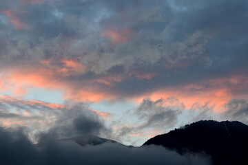Sonnenuntergang nach einem Regentag mit grauen und roten Wolken über dem Ultental bei Meran in Südtirol	