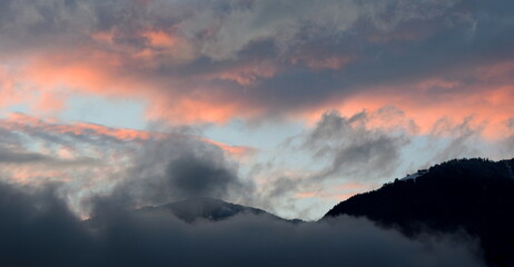 Sonnenuntergang nach einem Regentag mit grauen und roten Wolken über dem Ultental bei Meran in Südtirol	