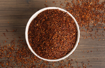 Dry rooibos leaves on wooden table, flat lay