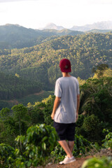 Fototapeta na wymiar Defocused young man wearing red cap with focus on mountains landscape in background.
