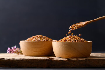 Golden flax seed in bowl on wooden with black background