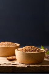 Golden flax seed in bowl on wooden with black background