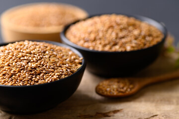 Close up of golden flax seed in bowl on wooden background