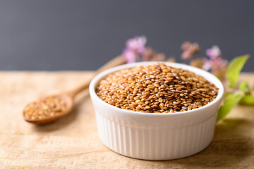 Close up of golden flax seed in bowl on wooden background