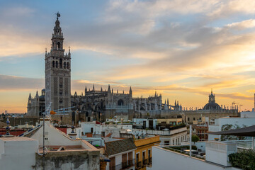 Sunset view from a rooftop overlooking the Andalusian city of Seville, Spain, with the Giralda Tower and the great Seville Cathedral in view over the skyline at early evening.