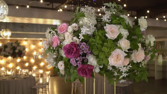 Flower arrangement at the party. Decorated with white and pink artificial flowers at a wedding reception. Tables with food ready for holiday dinner.