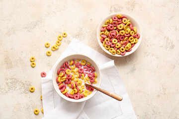 Bowls of colorful cereal rings on light grunge background