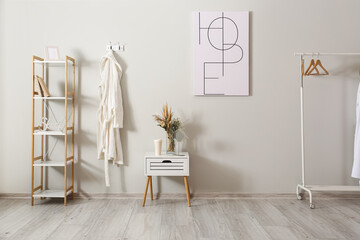 Interior of light room with white bathrobe and shelving unit