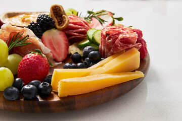 Cheese board with hummus, fruit and vegetables on a white background