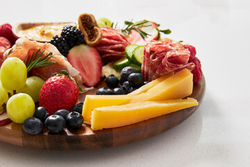 Cheese board with hummus, fruit and vegetables on a white background