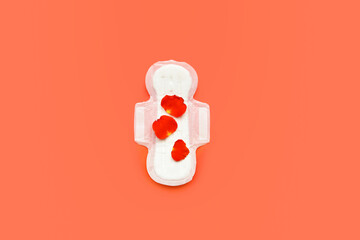Petals and menstrual pad on red background