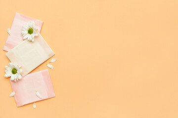 Flowers and menstrual pads on color background