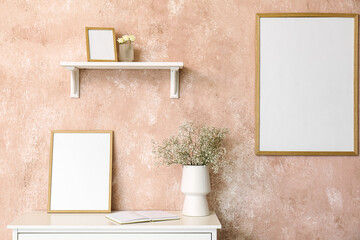 Vase with gypsophila flowers, book and frame on shelf near pink wall