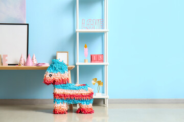Table with frame, shelving unit and Mexican pinata for Birthday party near blue wall