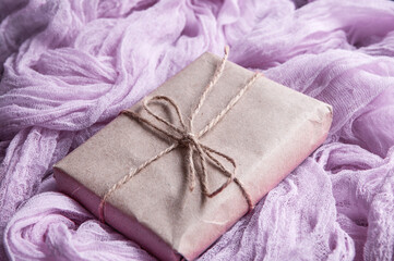 Obraz na płótnie Canvas Kraft paper box next to a vintage tablecloth hand-painted with pink gauze.
