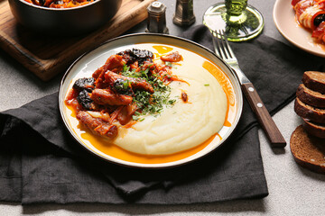 Plate with delicious mashed potatoes, gravy and beef stew with prunes on dark table